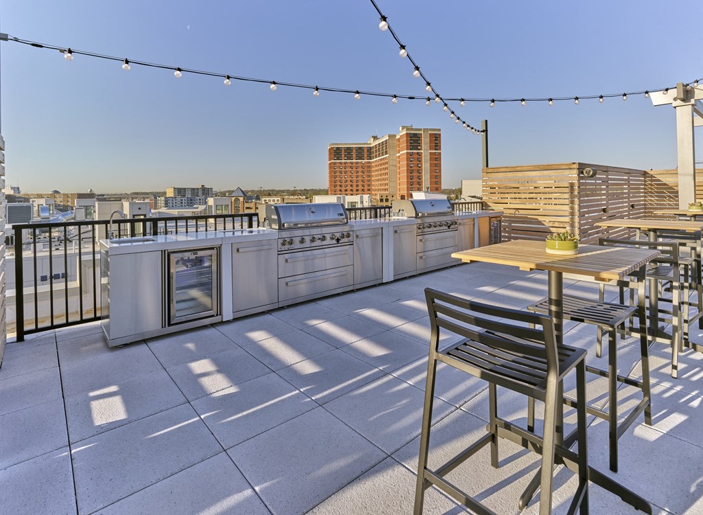 a rooftop patio with tables and chairs and a view of the city