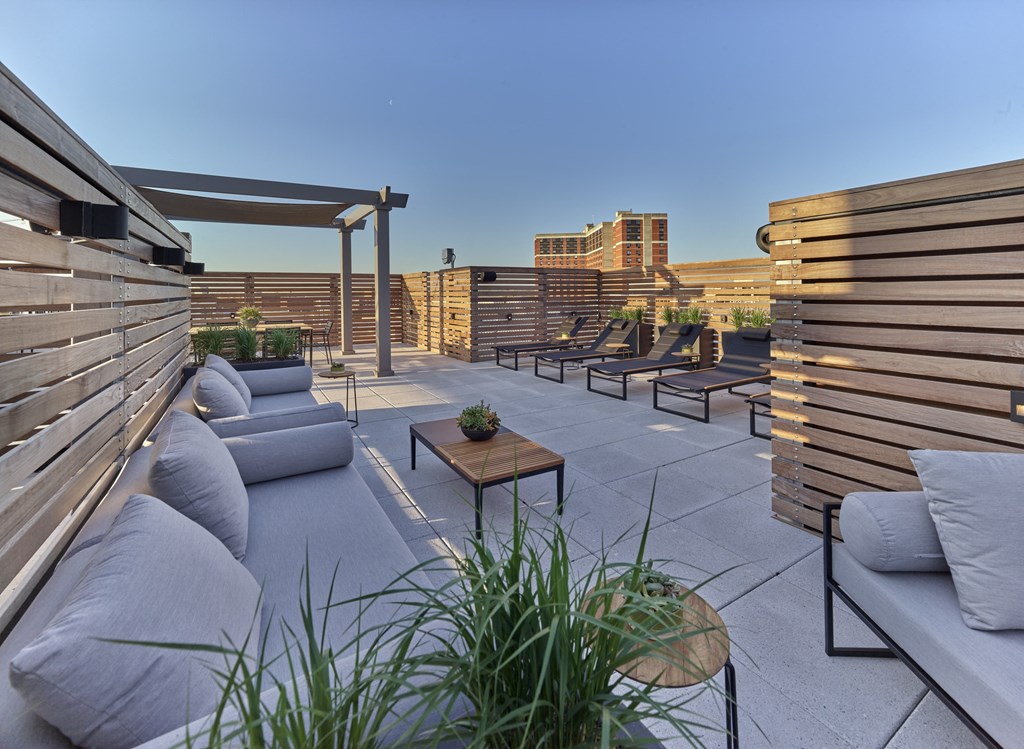 a rooftop patio with couches and tables and a city in the background