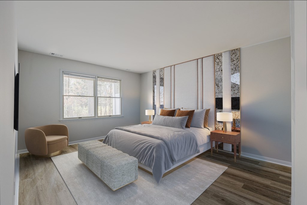 A spacious bedroom at The Village at Bridgewater in Bridgewater, NJ. Features large windows for natural light, neutral walls, and wood-style flooring for a modern and inviting atmosphere.