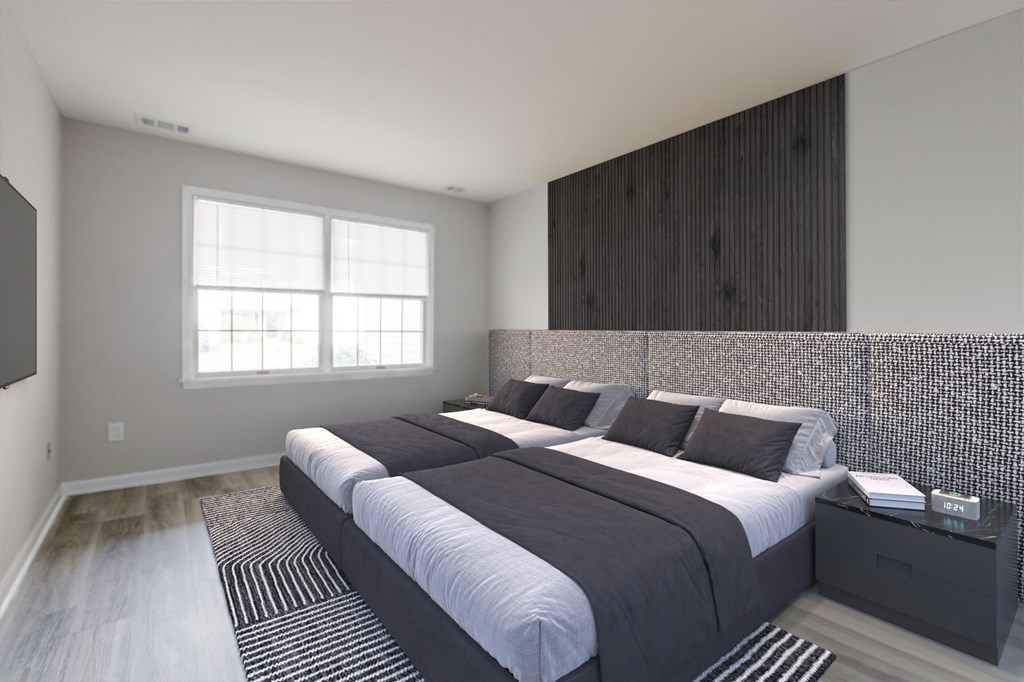 A contemporary bedroom layout at The Village at Bridgewater in Bridgewater, NJ. Large windows provide ample sunlight, complemented by modern flooring and neutral wall colors.