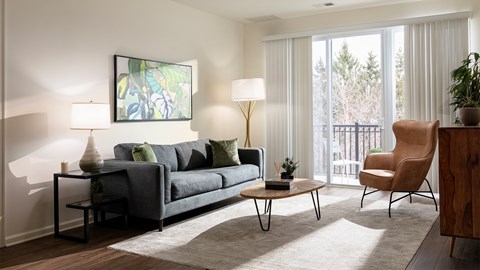 A living room with a grey couch, a wooden table, and a painting on the wall.