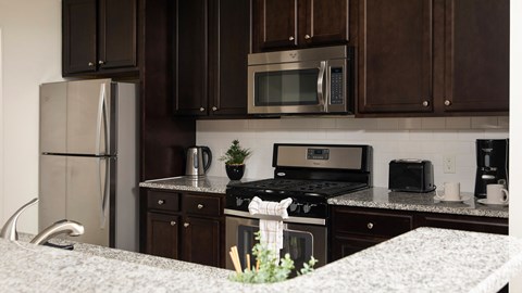 A kitchen with brown cabinets and a stainless steel refrigerator.