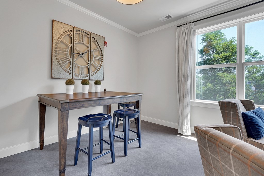 a living room with a table with three stools and a clock on the wall