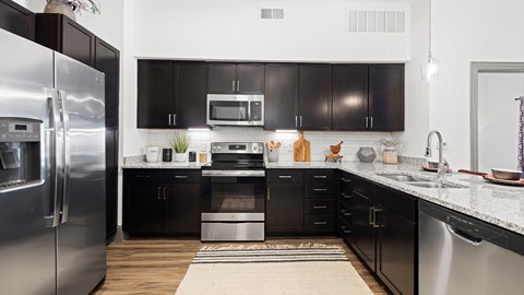 A modern kitchen with black cabinets and stainless steel appliances.