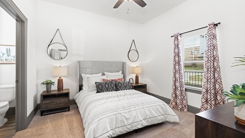 Model apartment bedroom at Reatta Ranch, with neutral decor, upholstered bed, and walk-in closet visible through the doorway.