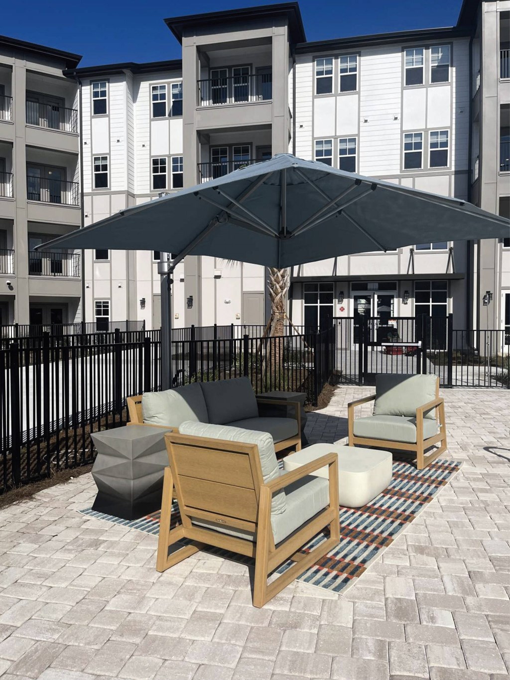 A patio with a black umbrella and two chairs.