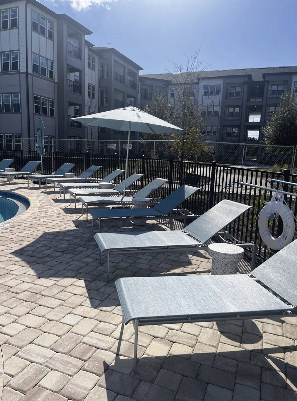 A poolside area with sun loungers and a white umbrella.