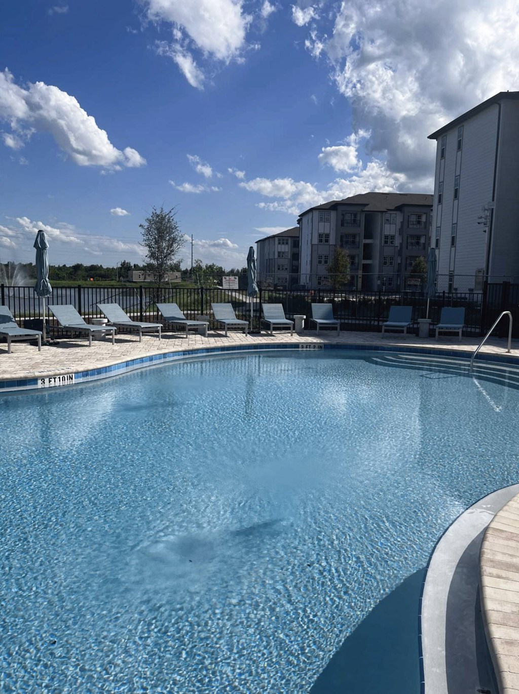 A large swimming pool with a wooden deck and lounge chairs.