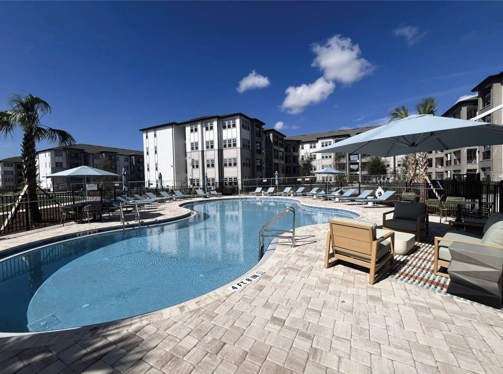 A large swimming pool surrounded by lounge chairs and umbrellas.