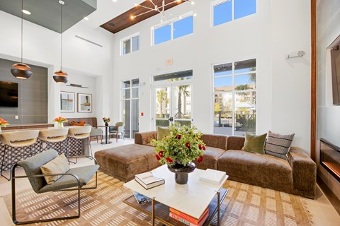 A living room with a brown couch, a coffee table, and a large window.