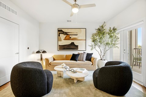 A living room with a white couch, two black chairs, and a coffee table.
