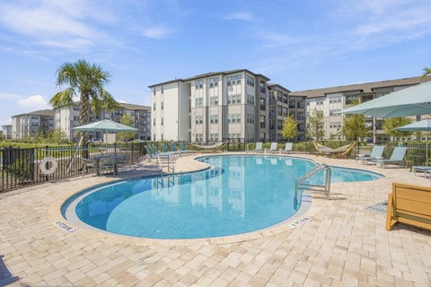 A swimming pool surrounded by a tiled patio and lounge chairs.