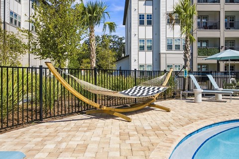A yellow hammock is strung between two metal posts on a patio.