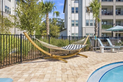 A yellow hammock is strung between two poles on a patio.
