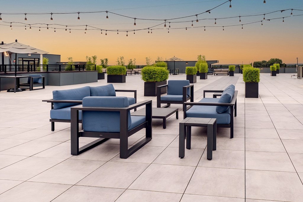 Spacious rooftop area with lounge furniture, string lights and skylines views at The Botanic apartments in Carteret, NJ