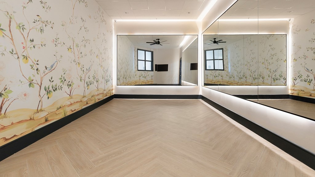 Bright and elegant yoga studio at The Mews at Princeton Junction, featuring full-length mirrors, natural wood flooring, and artistic wall design for wellness-focused living near Princeton Junction.
