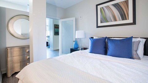 A bedroom with a large bed and a painting on the wall.