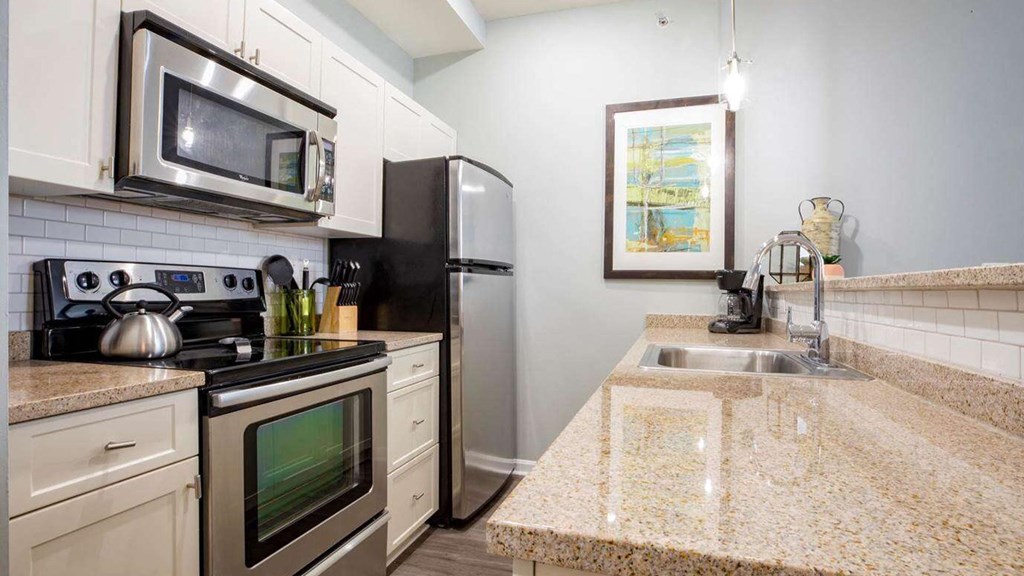 Apartment kitchen with white cabinets and granite countertops at The Pepper Building