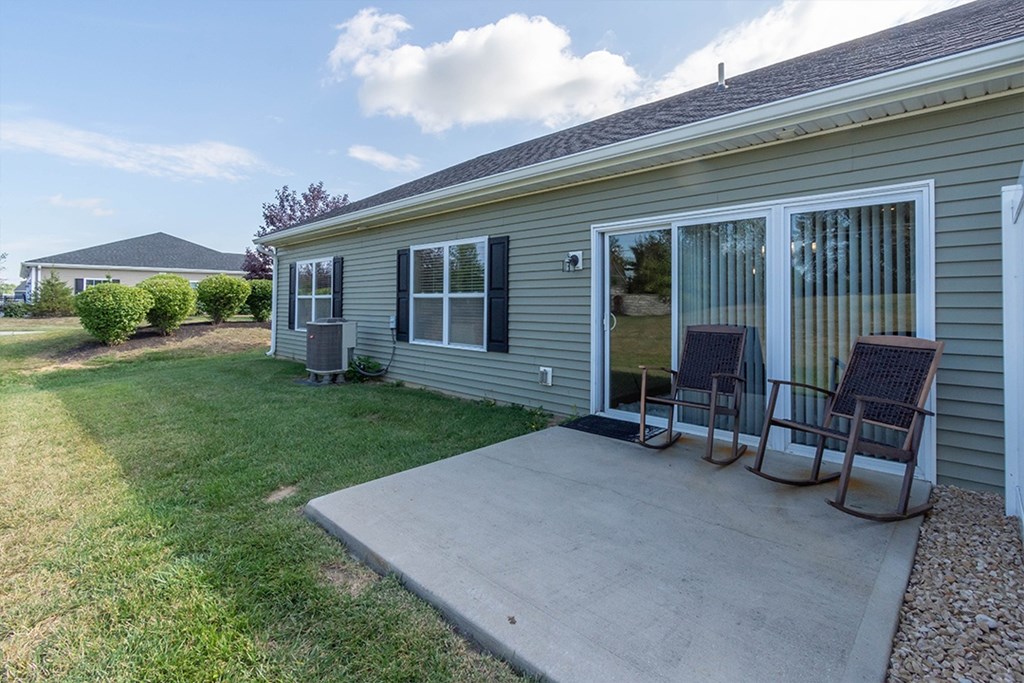 A house with a grey siding and a grey roof with a patio and two chairs.