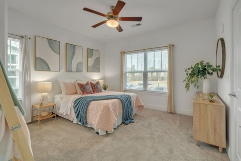 A bedroom with a bed, a plant, and a fan.