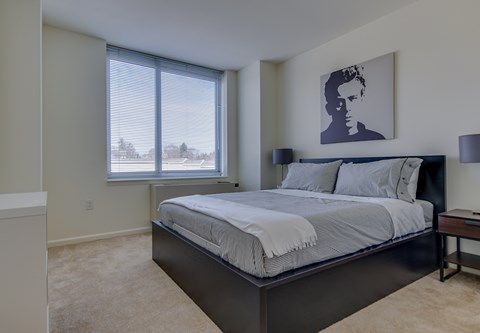 A bedroom with a large bed and a picture of a man on the wall.