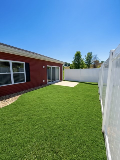 A red building with a white fence and green grass in front.