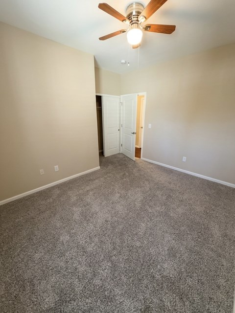 A room with a ceiling fan and carpeted floor.