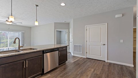 A kitchen with dark wood cabinets and a stainless steel dishwasher at The Villages of Florence and Weaver Mill