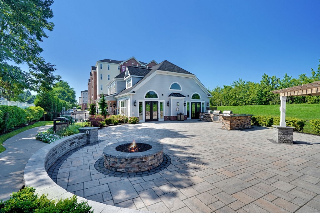 a patio with a fire pit and a house in the background