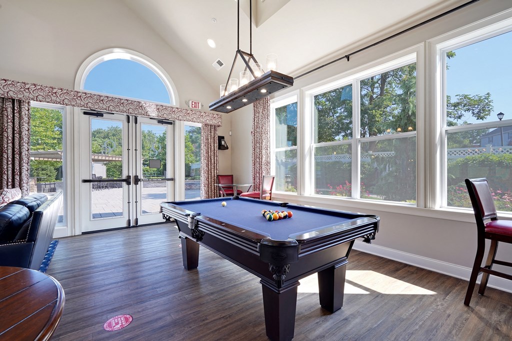 a game room with a pool table and large windows