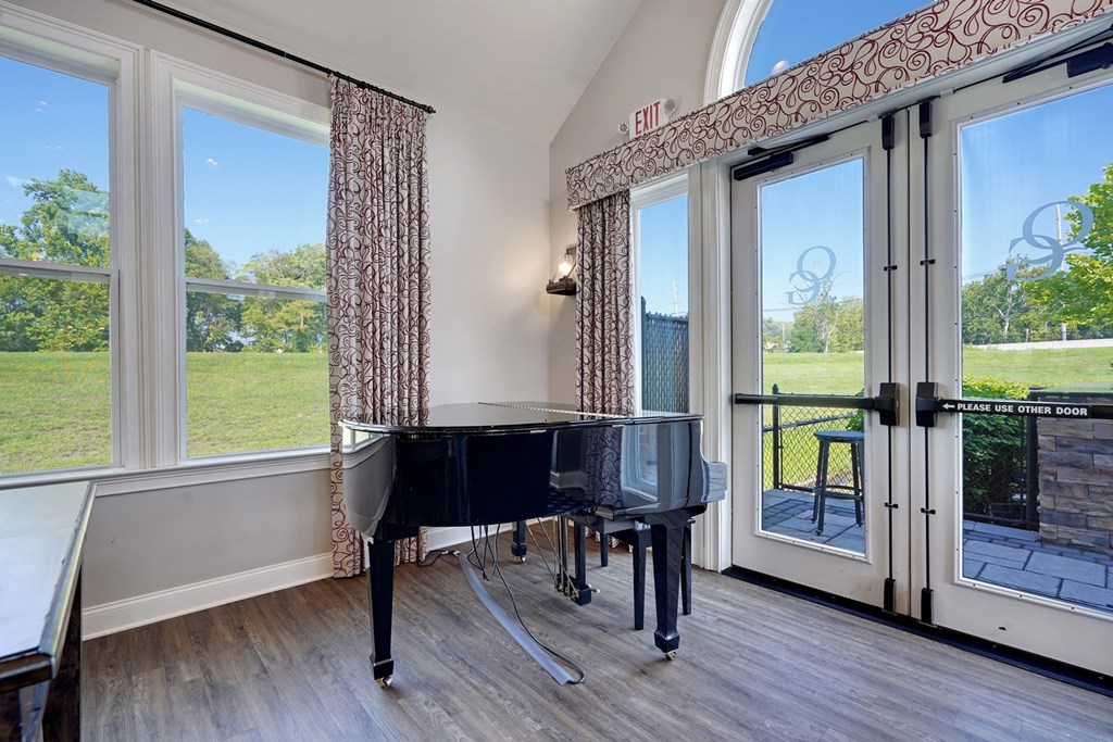 a piano in a room with windows and a glass door