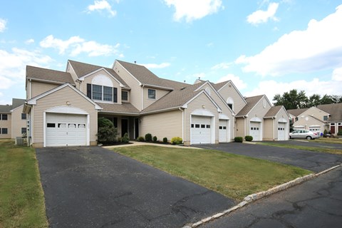 a row of houses with white garage doors and asphalt driveway