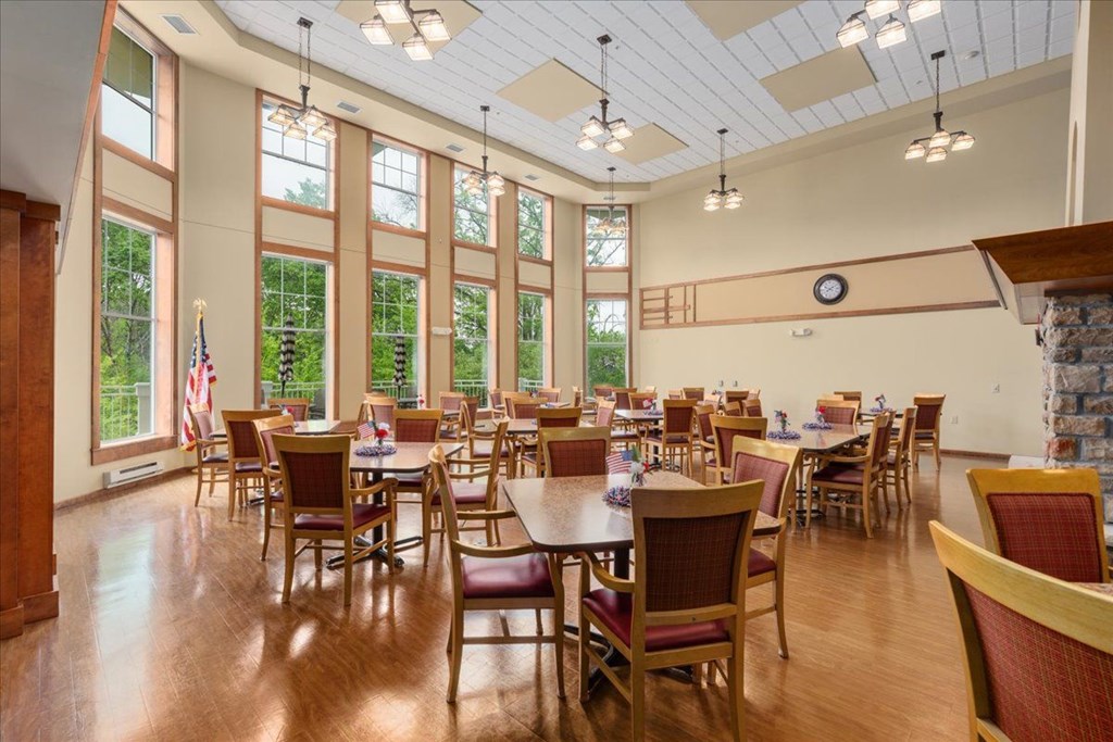 A large room with tables and chairs and a clock on the wall.