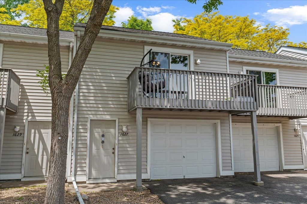 A tree stands in front of a two-story apartment building.