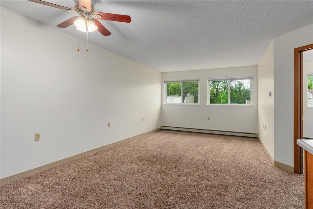 A room with a ceiling fan and carpeted floor.