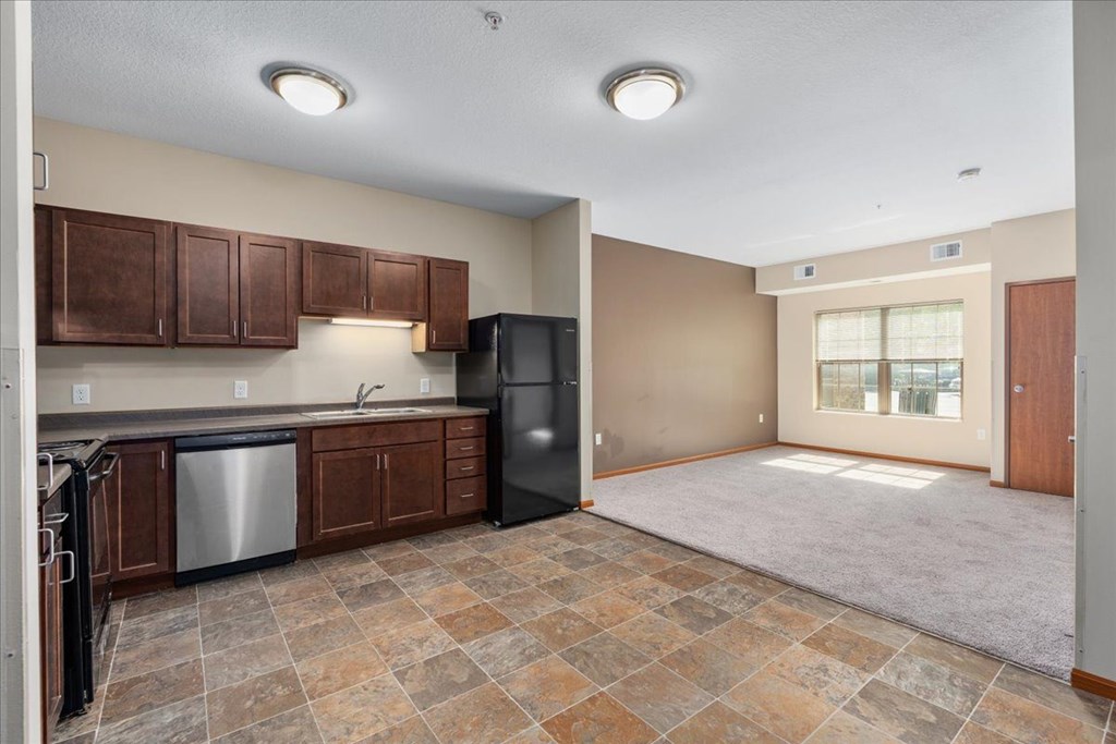 A kitchen with brown cabinets and a black refrigerator.