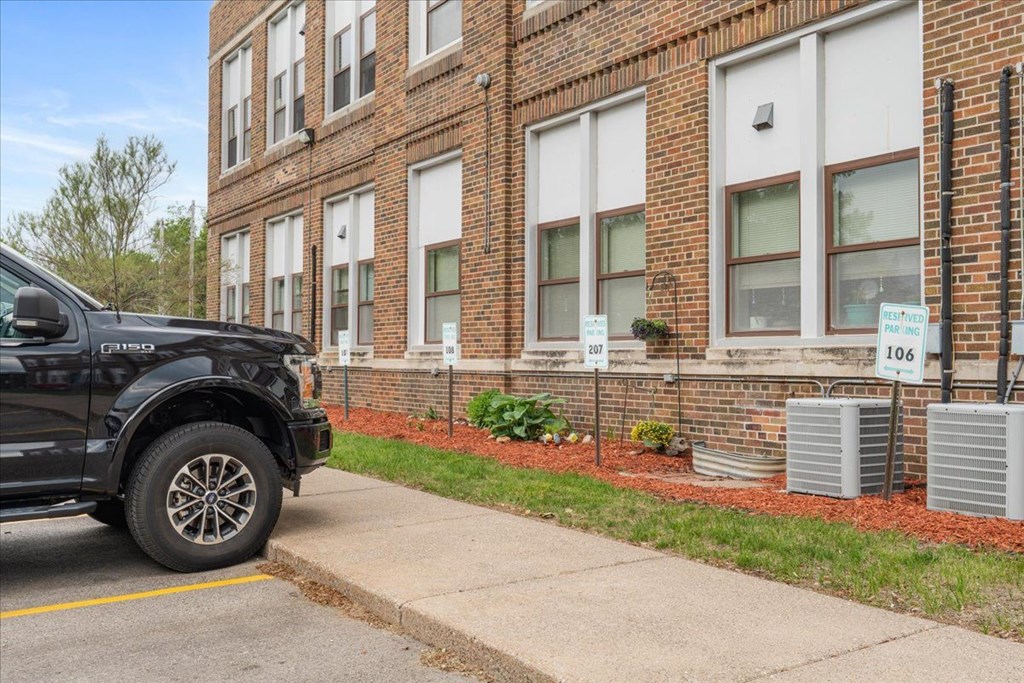 A black truck is parked on the side of a street in front of a brick building.