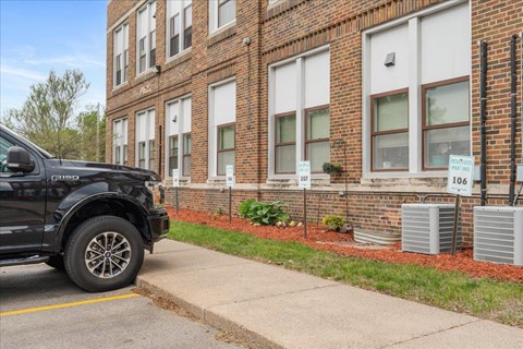 A black truck is parked on the side of a street in front of a brick building.
