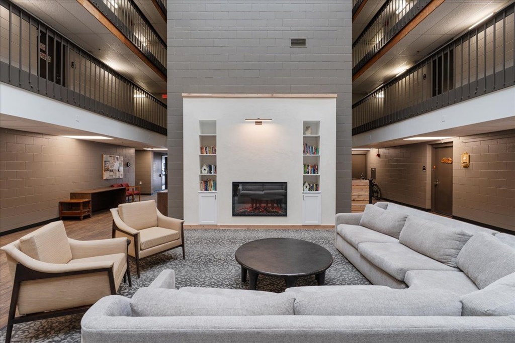 A living room with a fireplace and a grey couch.