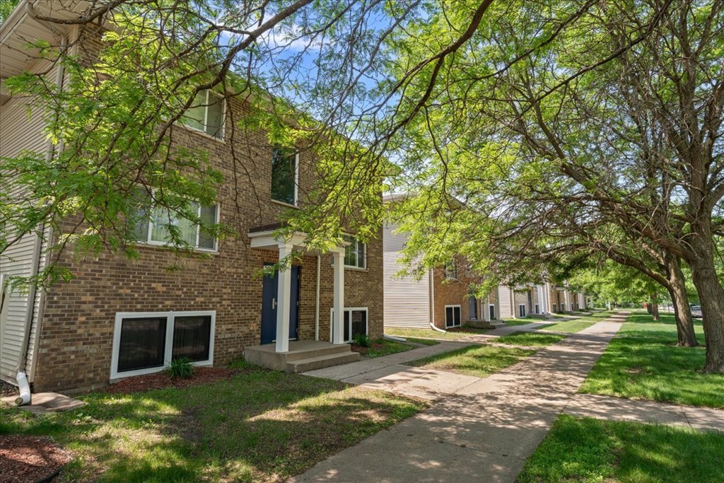A tree-lined street with apartment buildings on either side.