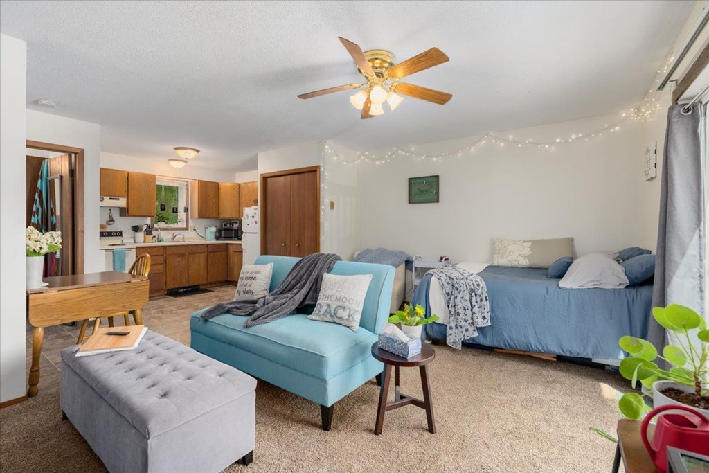 A living room with a blue couch and a ceiling fan.