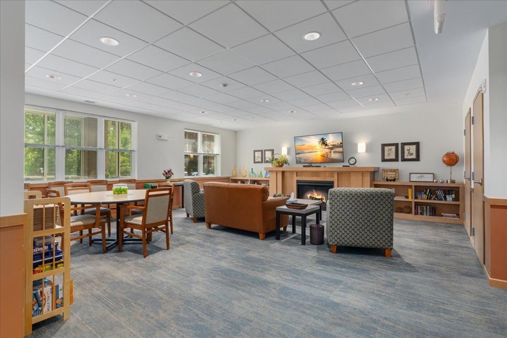 A spacious room with a fireplace, chairs, and a dining table.