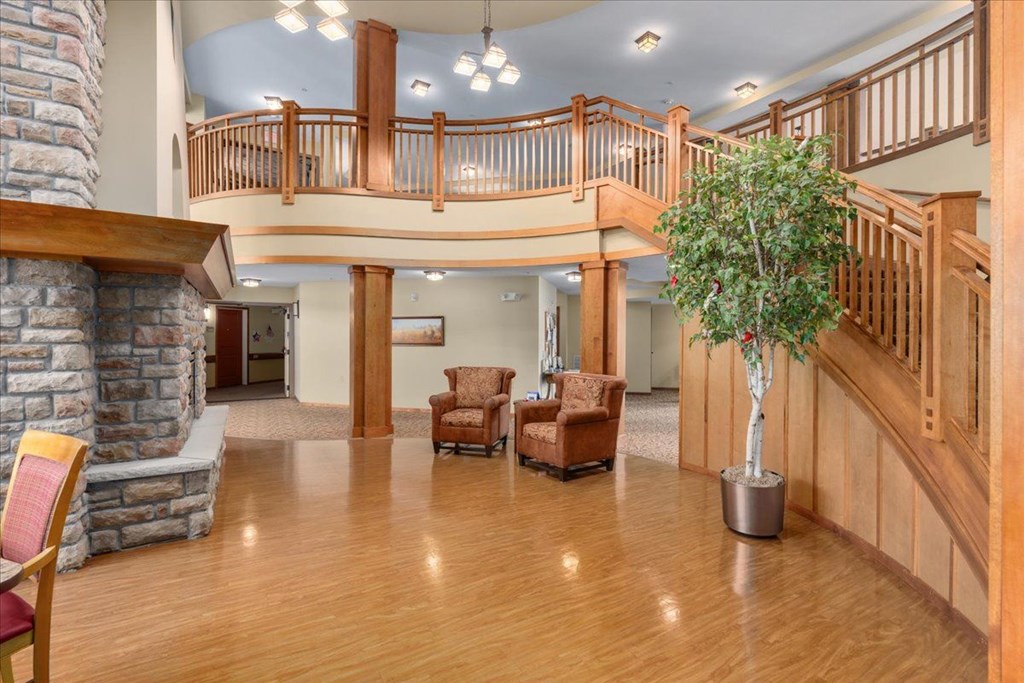 A living room with a stone fireplace and wooden floors.