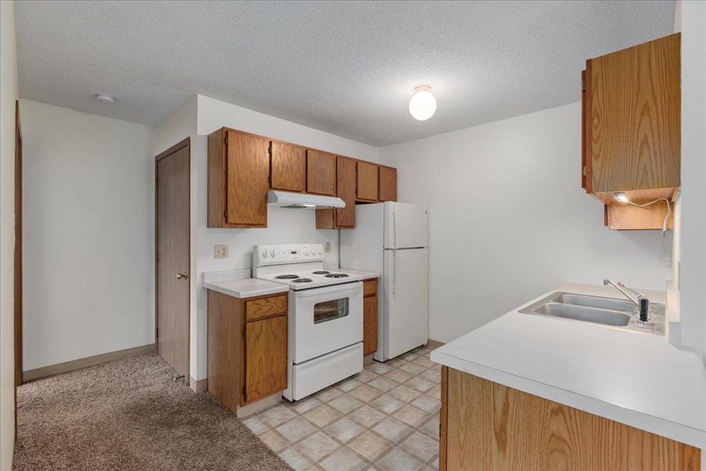 A kitchen with white appliances and wooden cabinets.