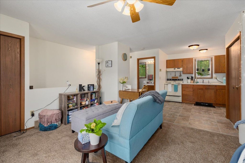 A living room with a blue couch and a ceiling fan.