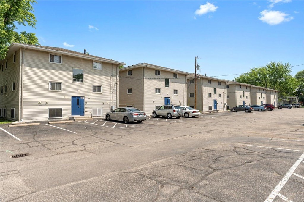 A parking lot in front of a building with several cars parked.