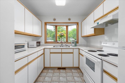 A kitchen with white cabinets and a window.
