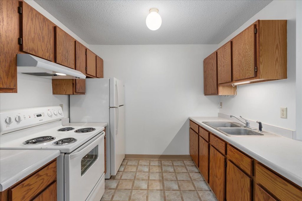 A kitchen with white appliances and wooden cabinets.