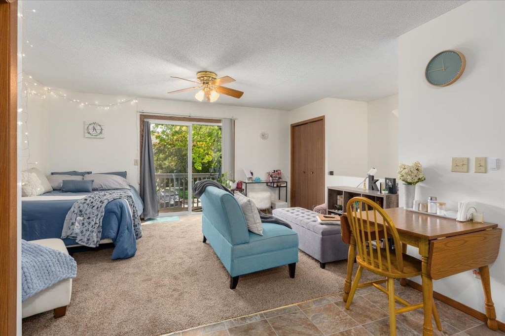 A bedroom with a bed, chair, and table.