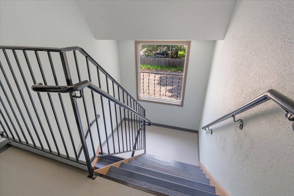 A staircase with a metal railing and steps leading up to a window.